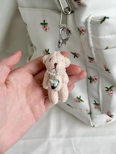 a person is holding a small teddy bear keychain