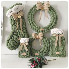 several knitted wreaths are displayed on the wall next to each other and tied with twine