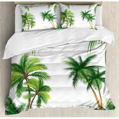 a bed covered in white sheets with green palm trees on it and two pillow cases