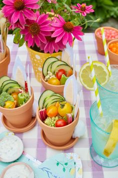 a table topped with bowls filled with fruit and veggies next to cups full of drinks