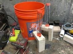 an orange bucket sitting on top of a floor next to tools