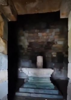 a stone fountain in the middle of a room with steps leading up to it's entrance