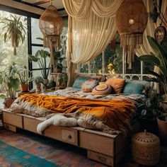 a bed with lots of pillows and blankets in a room filled with potted plants