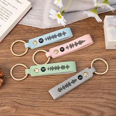 four different key chains sitting on top of a wooden table next to an open book