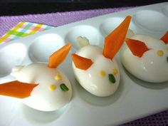 three small white eggs with carrots on them