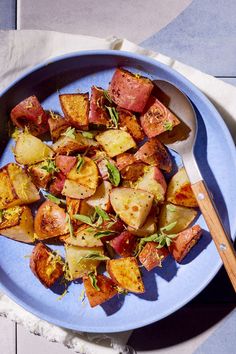 a blue plate topped with potatoes and meat next to a wooden spoon on top of a table