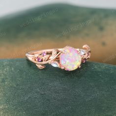 an opal and diamond ring sitting on top of a green surface