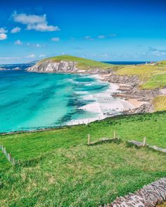 an ocean view from the top of a hill with green grass and blue water in the foreground