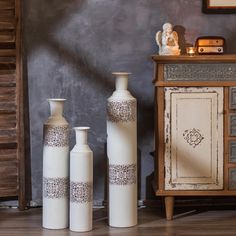 three white vases sitting on top of a wooden floor