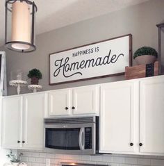 a kitchen with white cabinets and a sign that says happiness is homemade above the microwave