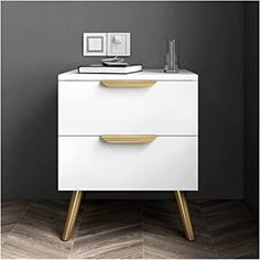 a white and gold dresser with two drawers in the middle, against a gray wall