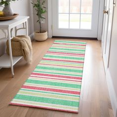 a bright striped rug is on the floor in front of a door with a potted plant