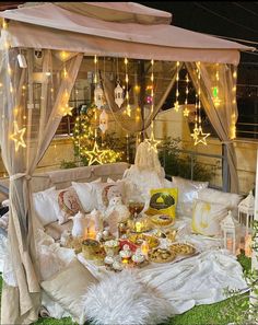 a bed covered in white blankets and lights next to a tree with stars on it