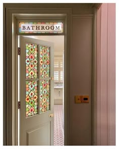 an open door with a stained glass window in the hallway leading to another room that has pink walls and white trim