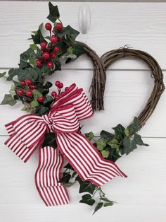 a heart shaped wreath with holly and red berries