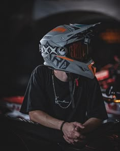 a man sitting down wearing a motorcycle helmet