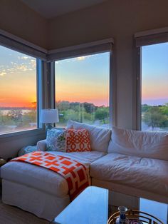 a living room filled with furniture and large windows overlooking the cityscape at sunset