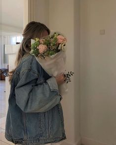 a woman is holding a bouquet of flowers in her hand and looking at the wall