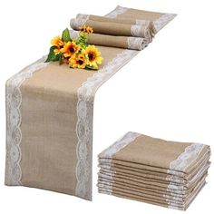 the table is covered with burlap and white lace, which has sunflowers on it