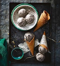 three scoops of ice cream on a tray next to two bowls and spoons