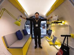 a man is standing in the middle of a room with yellow and gray furniture on display