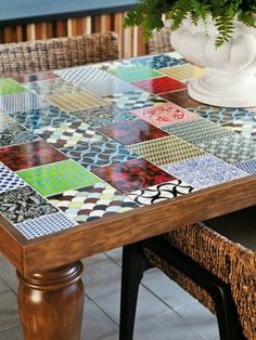 a wooden table topped with lots of colorful tile covered furniture and decorating items next to a potted plant