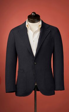 a suit jacket on a mannequin stand against a red background