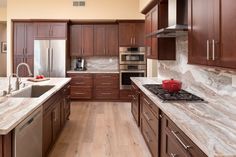 a kitchen with wooden cabinets and marble counter tops