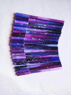 a stack of purple and blue pencils sitting next to each other on a white surface