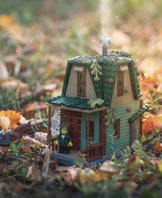 a toy house sitting in the middle of leaves