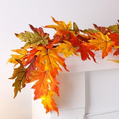 an arrangement of autumn leaves on a mantle