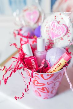 a cup filled with pink and white items on top of a table next to confetti