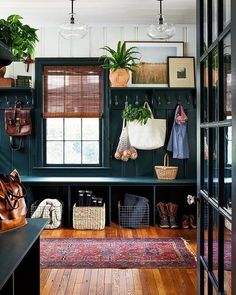 an entryway with green walls and lots of hanging baskets on the wall, shoes and purses