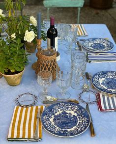 the table is set with blue and white plates, silverware, wine glasses, and flowers