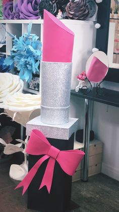 a large pink and silver cake sitting on top of a black box with a bow