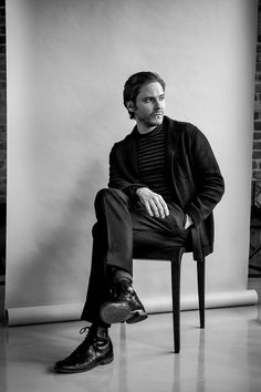 a man sitting in a chair with his foot on the ground and looking off to the side