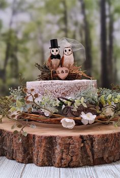 an owl figurine sitting on top of a tree stump in front of a wedding cake