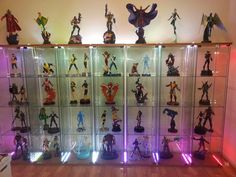 a display case filled with lots of action figures on top of wooden floor next to wall