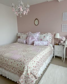 a bedroom with pink walls and bedding in the center, chandelier above