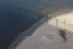 an aerial view of the beach and water with shadows on the sand, as seen from above