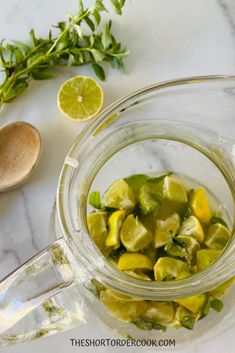 a glass jar filled with pickles next to a wooden spoon and lemon wedges