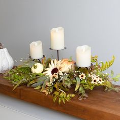 a table topped with candles and flowers on top of a wooden table next to a white pumpkin