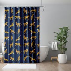 the shower curtain is decorated with gold cats on dark blue background, and has a white bathtub in front of it