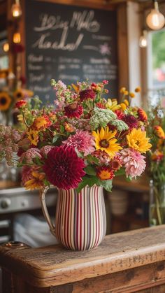 a vase filled with flowers sitting on top of a wooden table next to a chalkboard