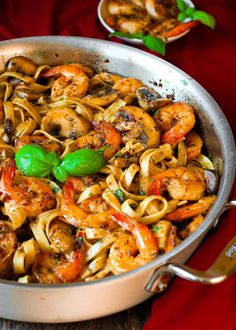 a pan filled with pasta and shrimp on top of a table