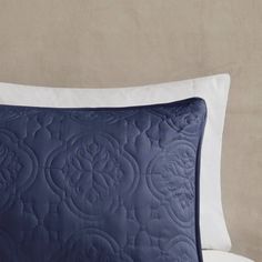 a blue and white pillow sitting on top of a bed