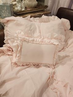 an unmade bed with pink ruffled sheets and pillows