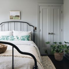 a bedroom with a bed, rug and potted plants on the side of the bed