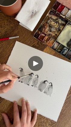 a person is painting on paper with watercolors