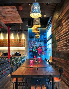 a restaurant with wooden tables and chairs in front of a chalkboard wall that has writing on it